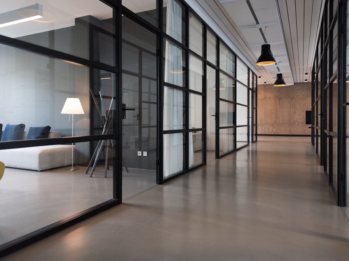Black and white photograph of a glass office corridor in a corporate building